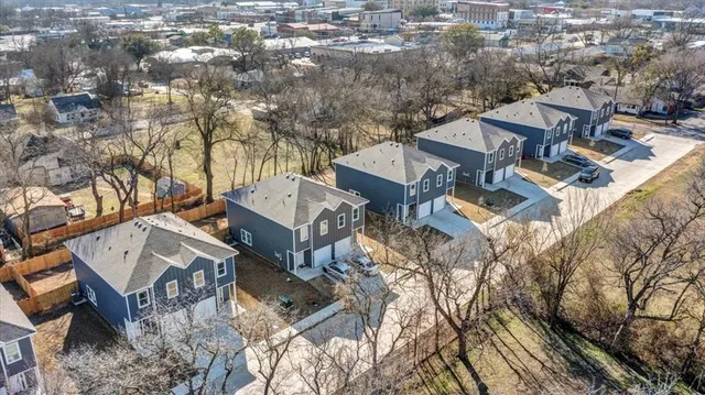 an aerial view of a residential houses with yard and mountain view in back