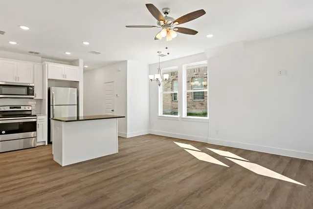 a view of a kitchen with a refrigerator a ceiling fan and wooden floor