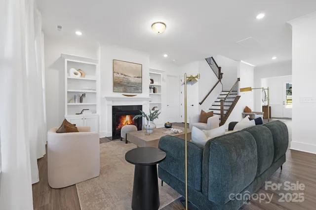 a living room with furniture kitchen view and a wooden floor