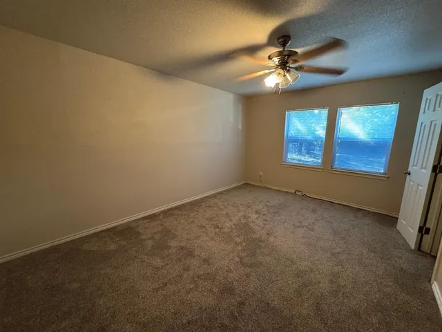 an empty room with a ceiling fan and window