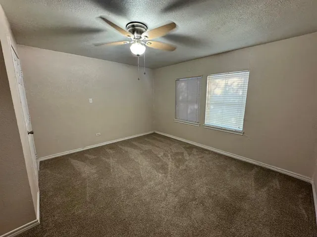 an empty room with a chandelier fan and windows