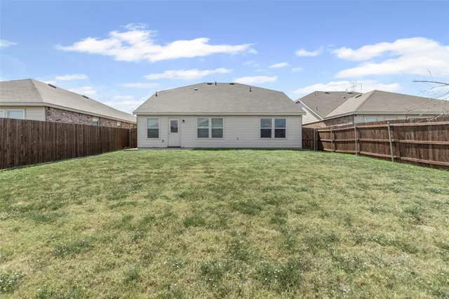 a view of a house with a yard and fence