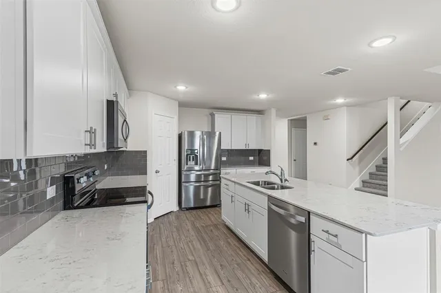 a kitchen with stainless steel appliances a sink a stove a refrigerator and cabinets