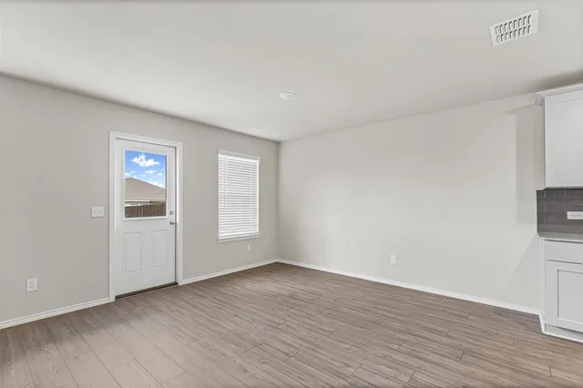 a view of an empty room with wooden floor and a window