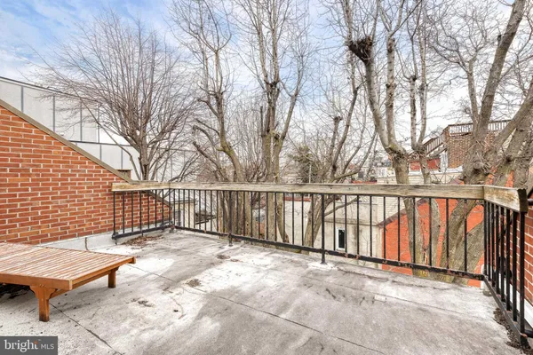 a view of a bench with wooden fence and trees