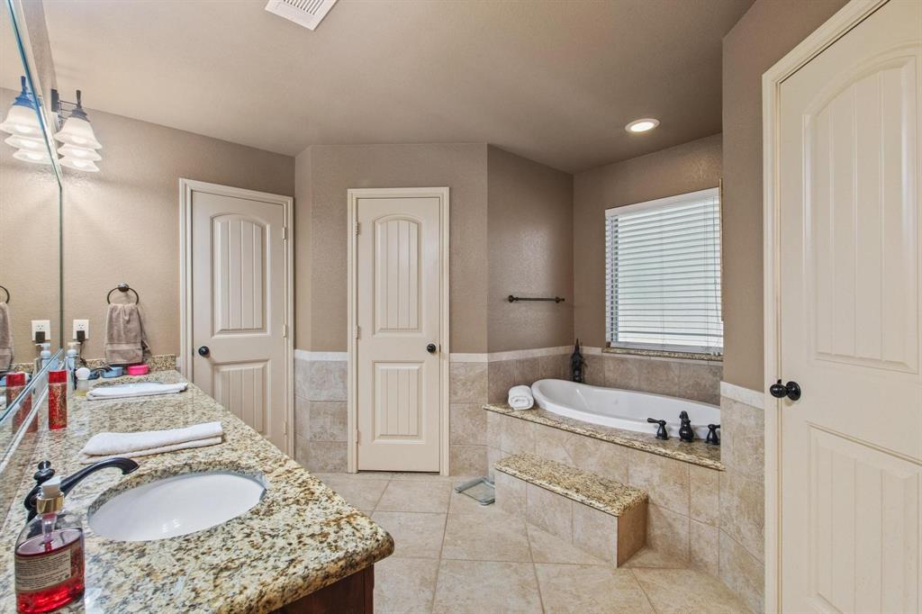 112 Knight Court Springtown, TX 76082 - Photo 16 of 26 Spa-inspired primary bathroom featuring dual vanities with granite countertops, an undermount sink, and polished chrome fixtures