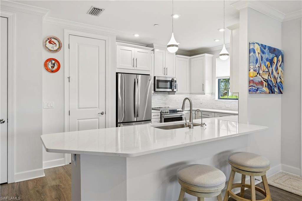 15245 Zeno Way, Unit 101 Naples, FL 34114 - Photo 8 of 46 a kitchen with stainless steel appliances a sink a refrigerator and a refrigerator