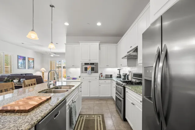 a kitchen with stainless steel appliances granite countertop a sink a stove and a refrigerator