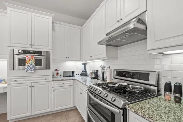 a kitchen with white cabinets and appliances
