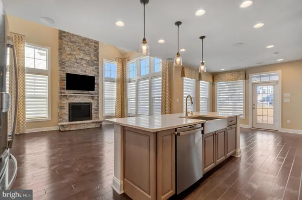 a kitchen with stainless steel appliances granite countertop a stove a oven a kitchen island and a wooden floor