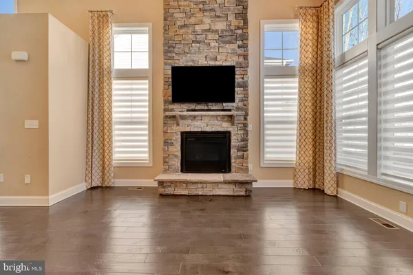 a view of an empty room with wooden floor and a fireplace