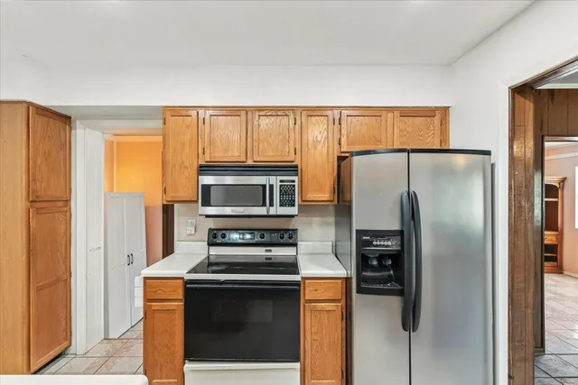 a kitchen with stainless steel appliances granite countertop a refrigerator a stove a microwave and wooden cabinets
