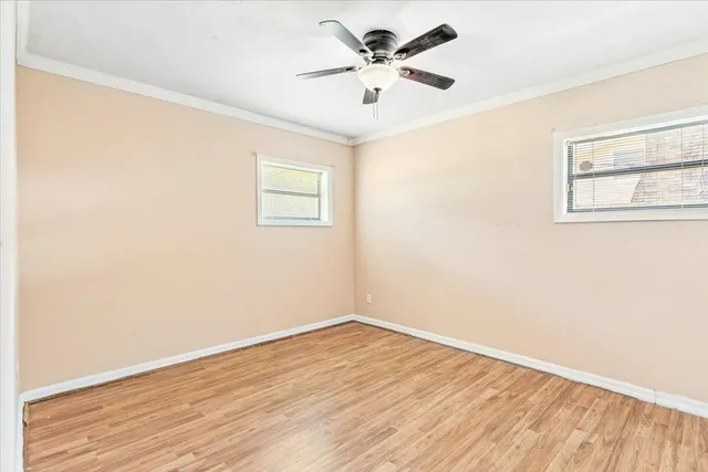 an empty room with wooden floor and a ceiling fan