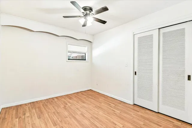 an empty room with wooden floor and fan