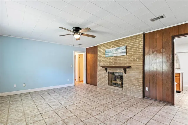 a view of an empty room with a fireplace and a chandelier fan