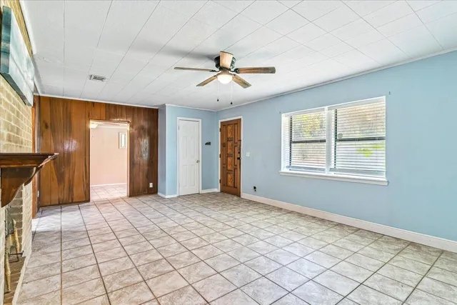 a view of an empty room with window and chandelier fan