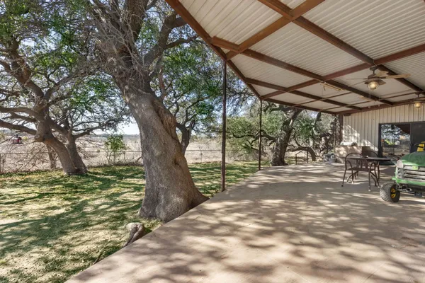 a view of a backyard with table and chairs and a large tree
