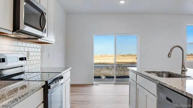 a kitchen with stainless steel appliances granite countertop a sink and a stove top oven with wooden floor