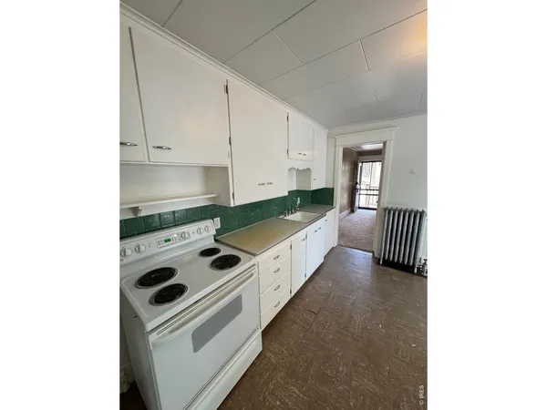 a kitchen with stainless steel appliances a stove a sink and white cabinets