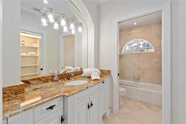 a bathroom with a granite countertop toilet a sink and a mirror