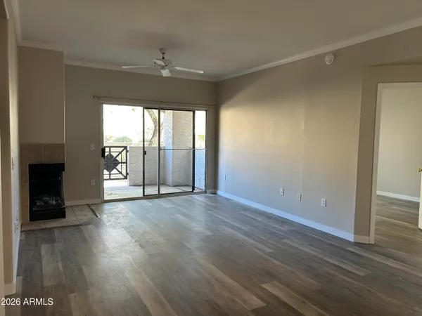 an empty room with wooden floor chandelier fan and windows