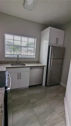 a kitchen with granite countertop a sink a stove and cabinets