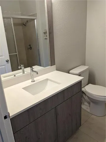 a bathroom with a toilet sink vanity granite and mirror