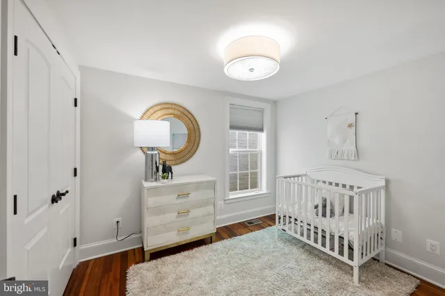 a bedroom with a baby bed a chandelier and dresser