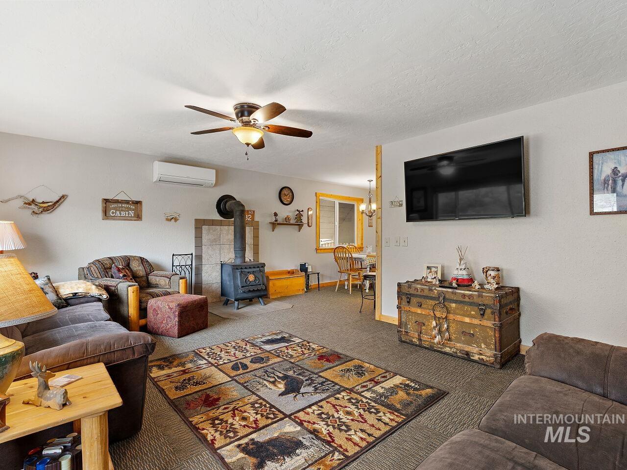 7438 Highway 95 Riggins, ID 83549 - Photo 20 of 36 Carpeted living area with a wood stove, ceiling fan, and a mini split for heating / cooling