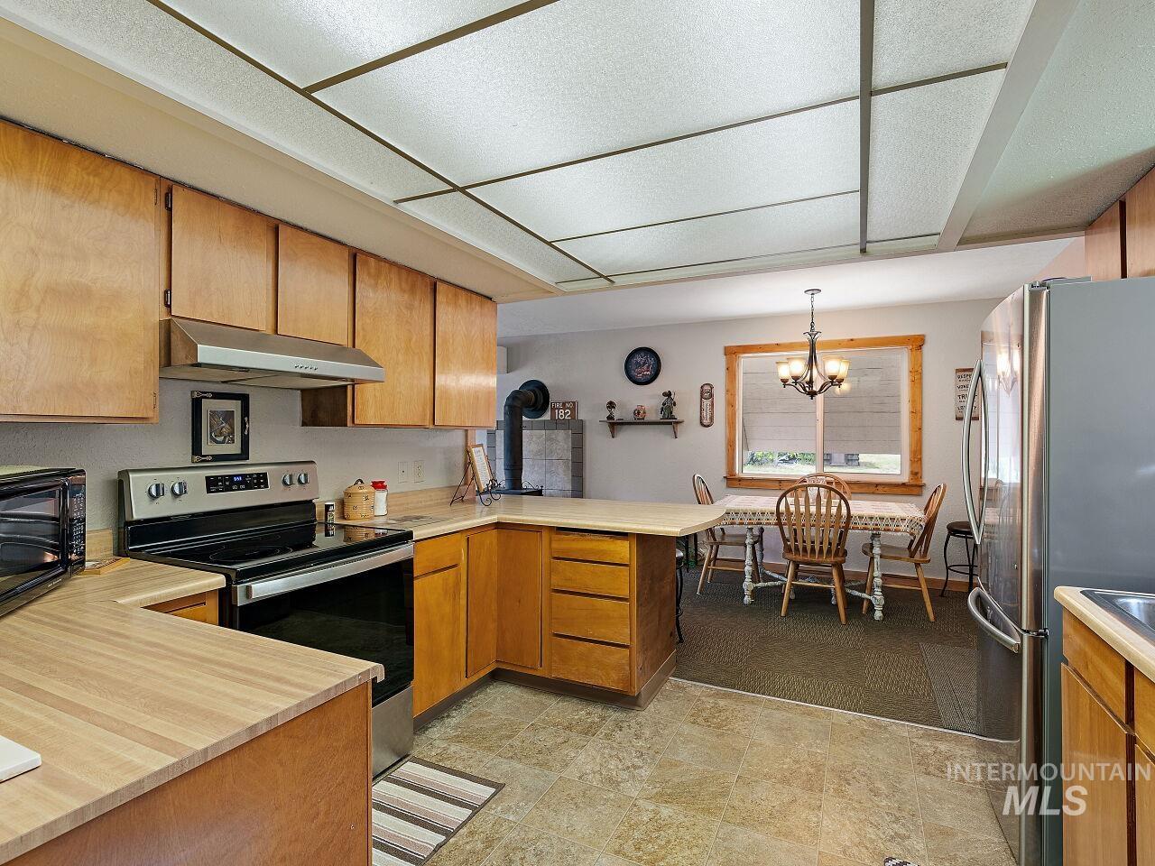 7438 Highway 95 Riggins, ID 83549 - Photo 23 of 36 Kitchen featuring a peninsula, stainless steel appliances, light countertops, wood finish cabinets, and a chandelier