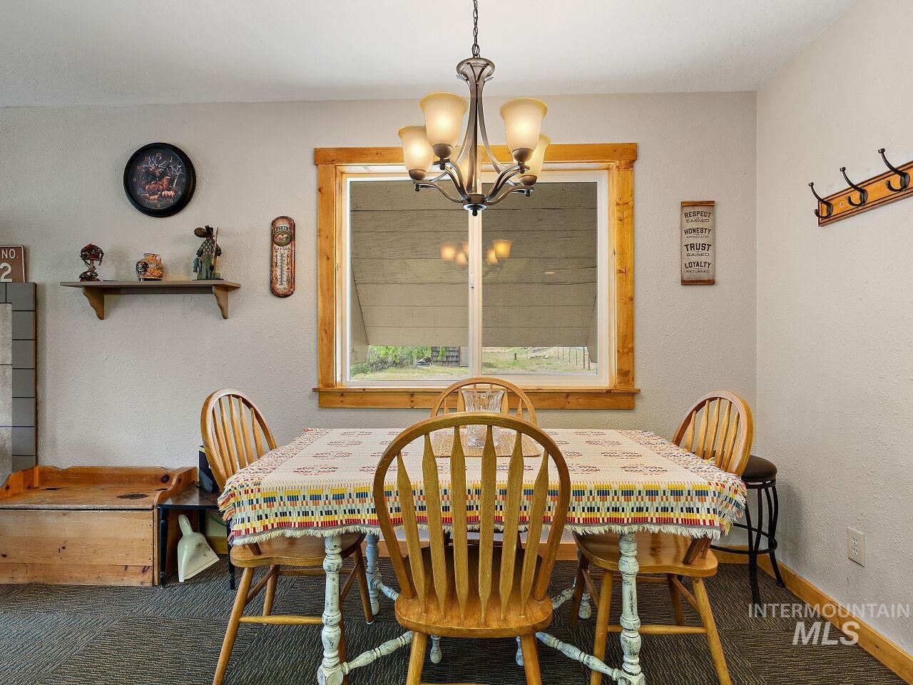 7438 Highway 95 Riggins, ID 83549 - Photo 25 of 36 Dining room with a textured wall, carpet flooring, and a chandelier