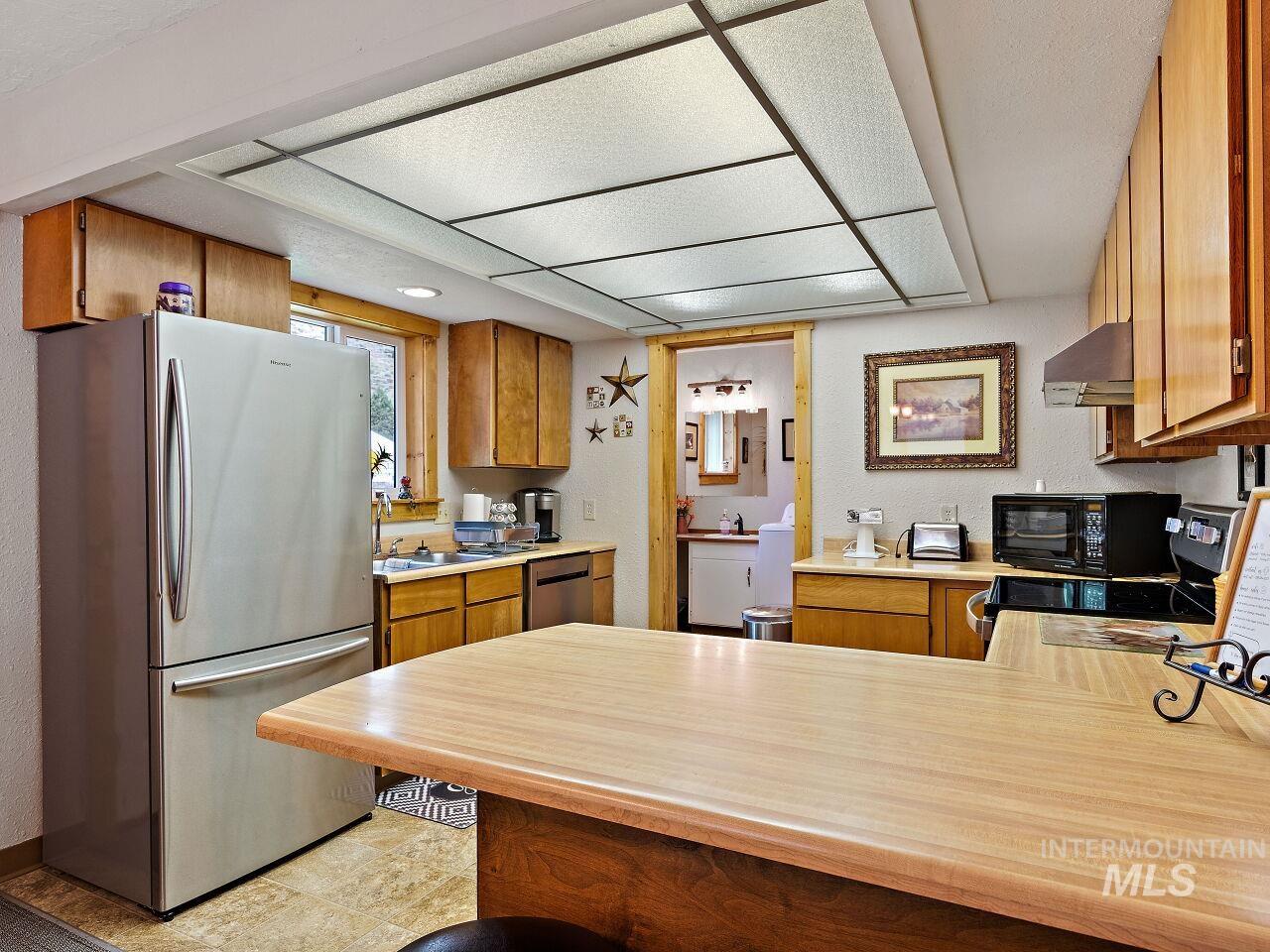7438 Highway 95 Riggins, ID 83549 - Photo 28 of 36 Kitchen featuring black appliances, a peninsula, light countertops, wood finish cabinetry, and a textured wall