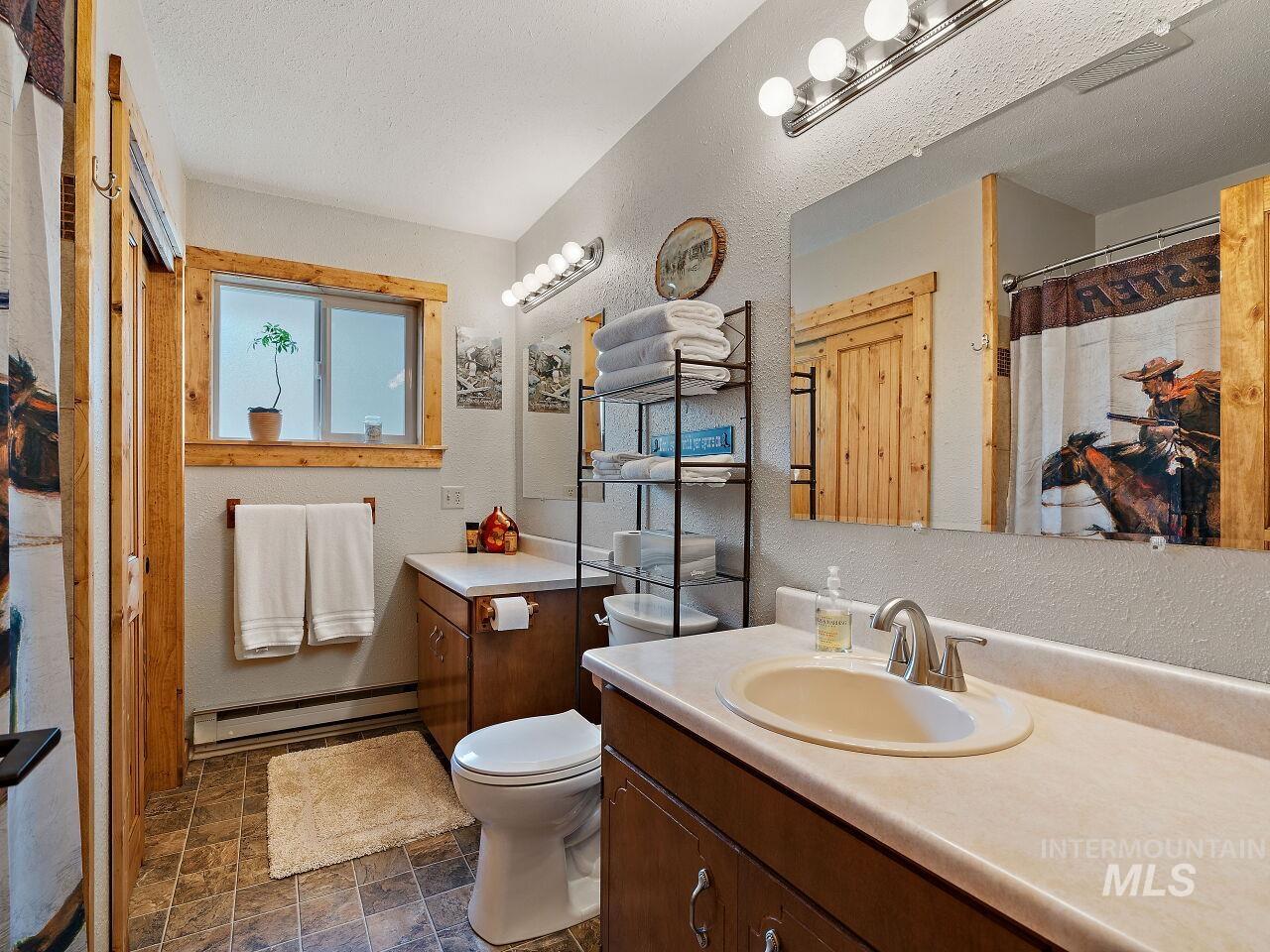 7438 Highway 95 Riggins, ID 83549 - Photo 33 of 36 Bathroom with vanity, a textured wall, baseboard heating, curtained shower, and stone finish floors