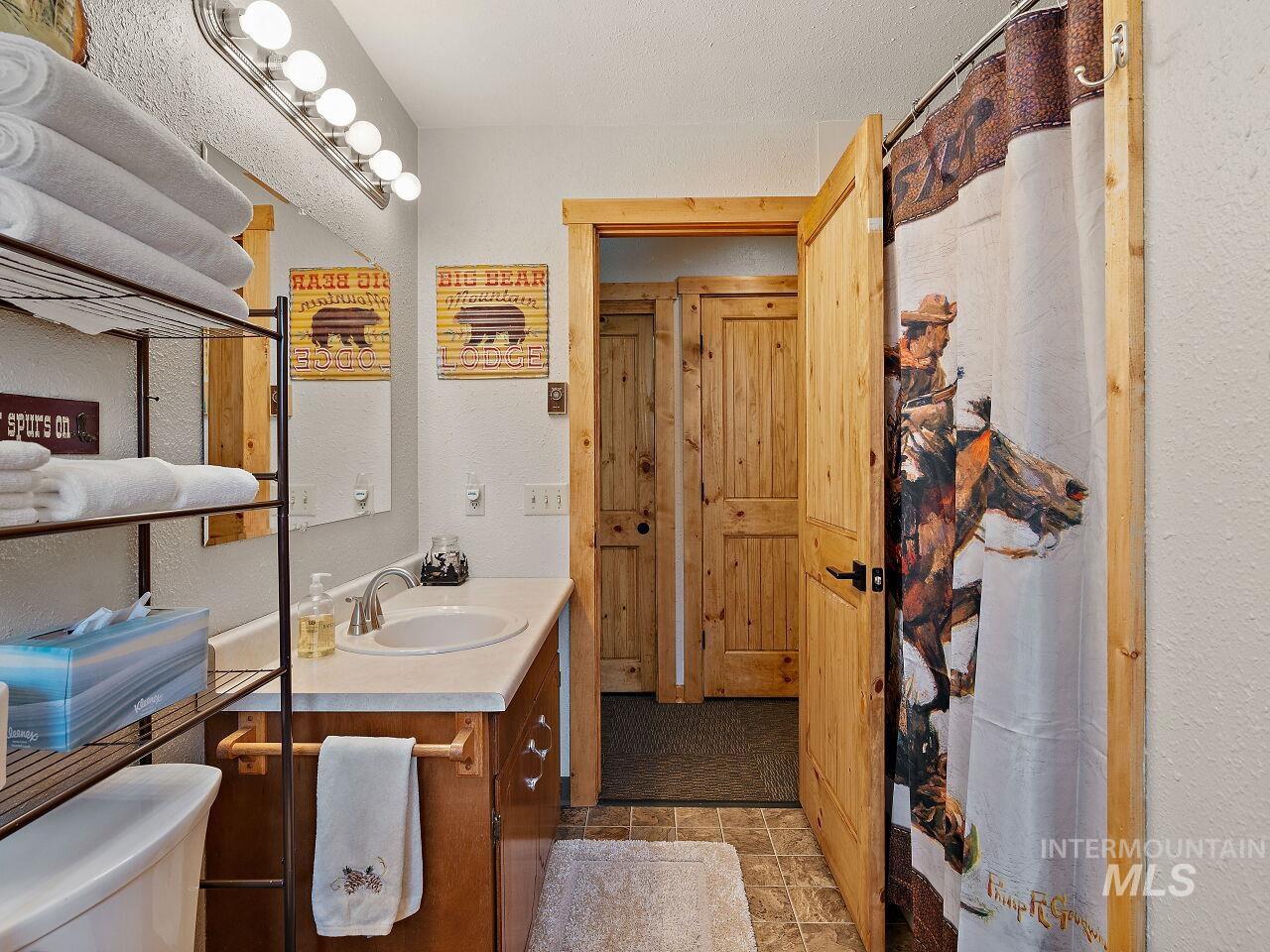 7438 Highway 95 Riggins, ID 83549 - Photo 34 of 36 Bathroom with vanity, a shower with curtain, light stone finish floors, a textured wall, and a textured ceiling