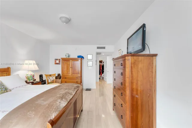 a spacious bedroom with a bed and a dresser with mirror