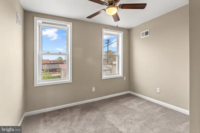 an empty room with windows and fan