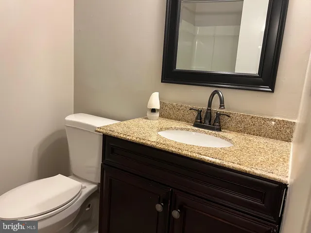 a bathroom with a granite countertop toilet sink and mirror