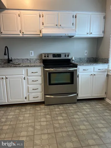 a kitchen with granite countertop white cabinets and appliances