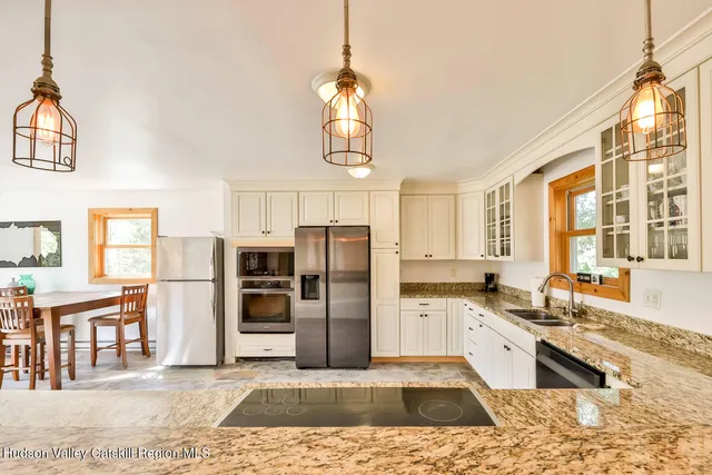 a kitchen with stainless steel appliances granite countertop a refrigerator a sink dishwasher a stove with wooden cabinets and floor