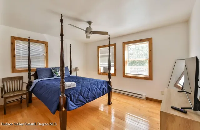 a spacious bedroom with a bed a window and flat screen tv