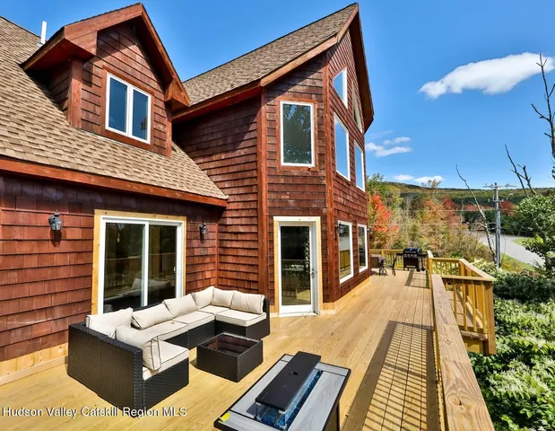 a view of a patio with couches table and chairs with wooden floor and fence