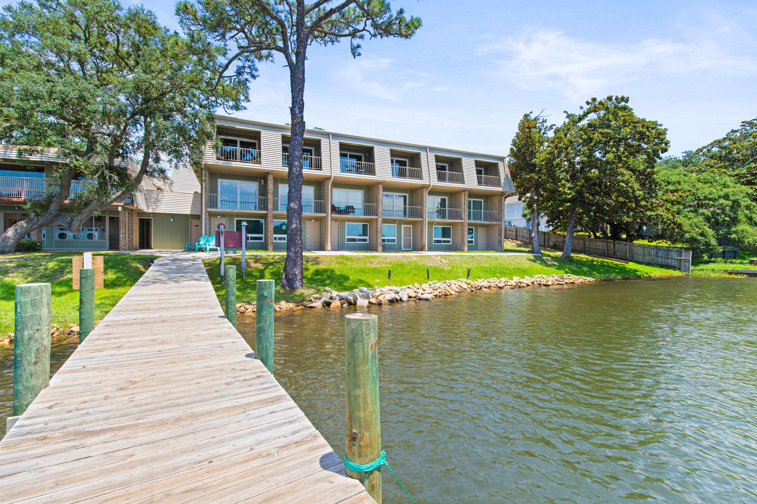 210 Pelham Road, Unit 109B Fort Walton Beach, FL 32547 - Photo 28 of 33 a view of a brick building next to a lake with a large tree