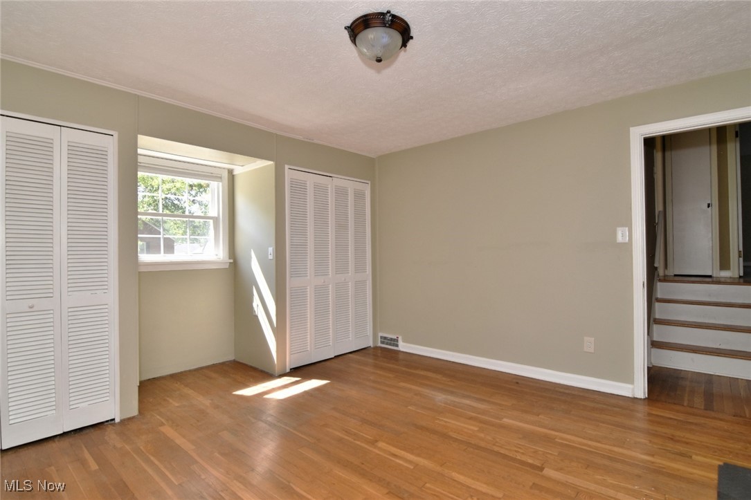 3679 Fenley Road Cleveland Heights, OH 44121 - Photo 31 of 45 Unfurnished bedroom featuring multiple closets, light wood-type flooring, and a textured ceiling
