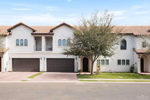 Mediterranean / spanish-style house featuring stucco siding, driveway, a balcony, a tiled roof, and an attached garage