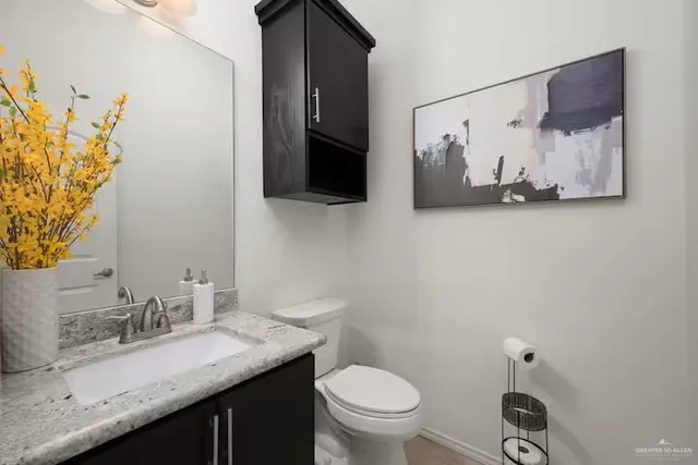 a bathroom with a granite countertop sink a toilet and mirror