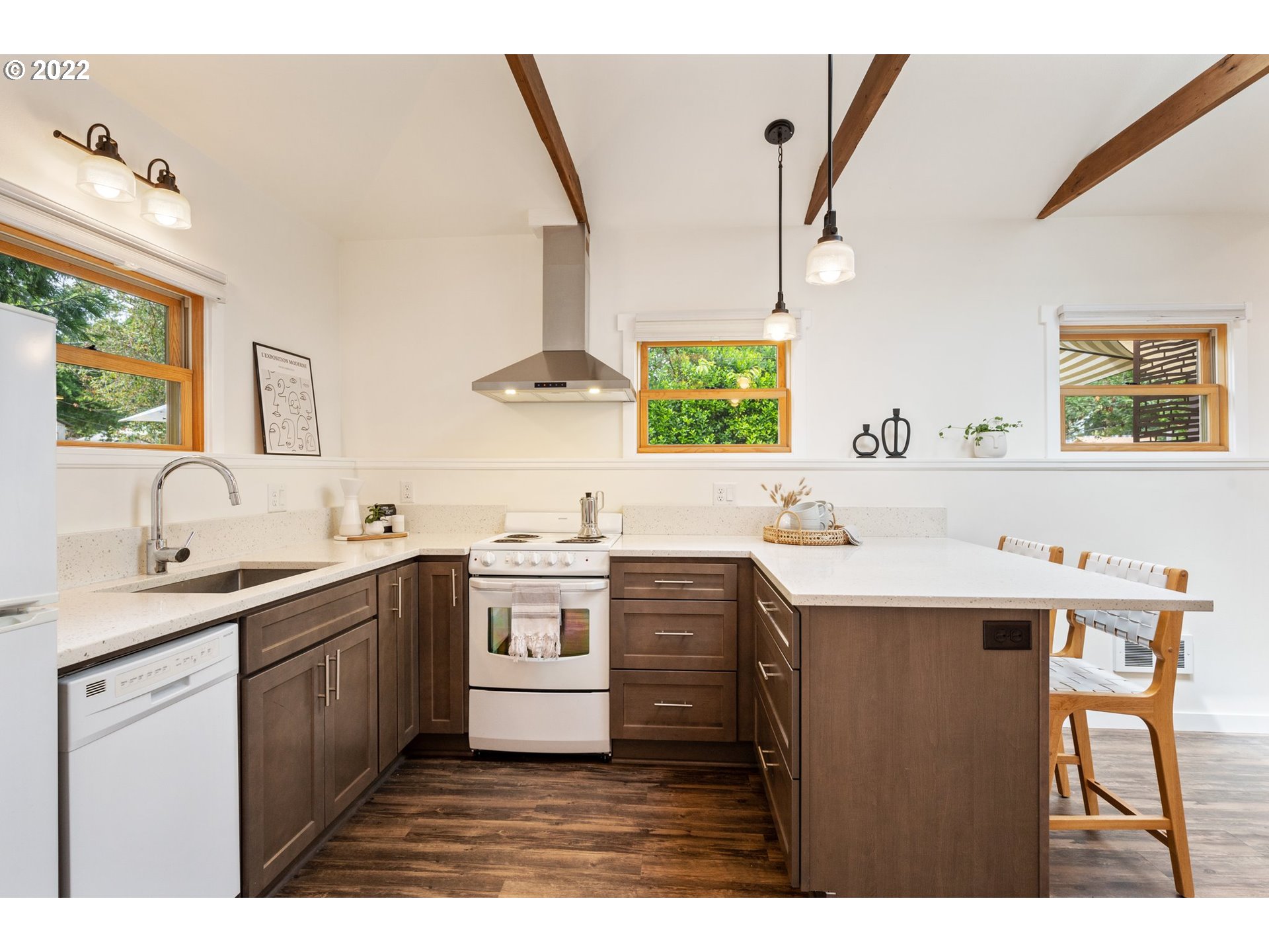 3286 Northeast Holman Street Portland, OR 97211 - Photo 4 of 25 a kitchen with stainless steel appliances kitchen island granite countertop a sink a stove a dining table and chairs with wooden floor