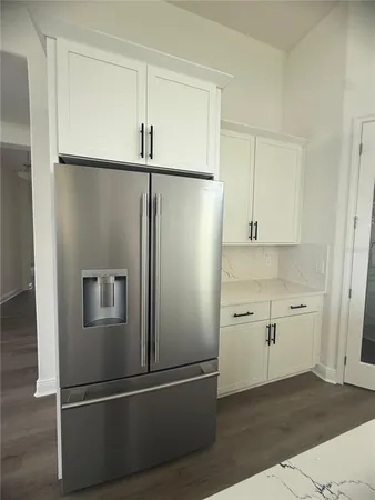 a view of a refrigerator in kitchen and white cabinets