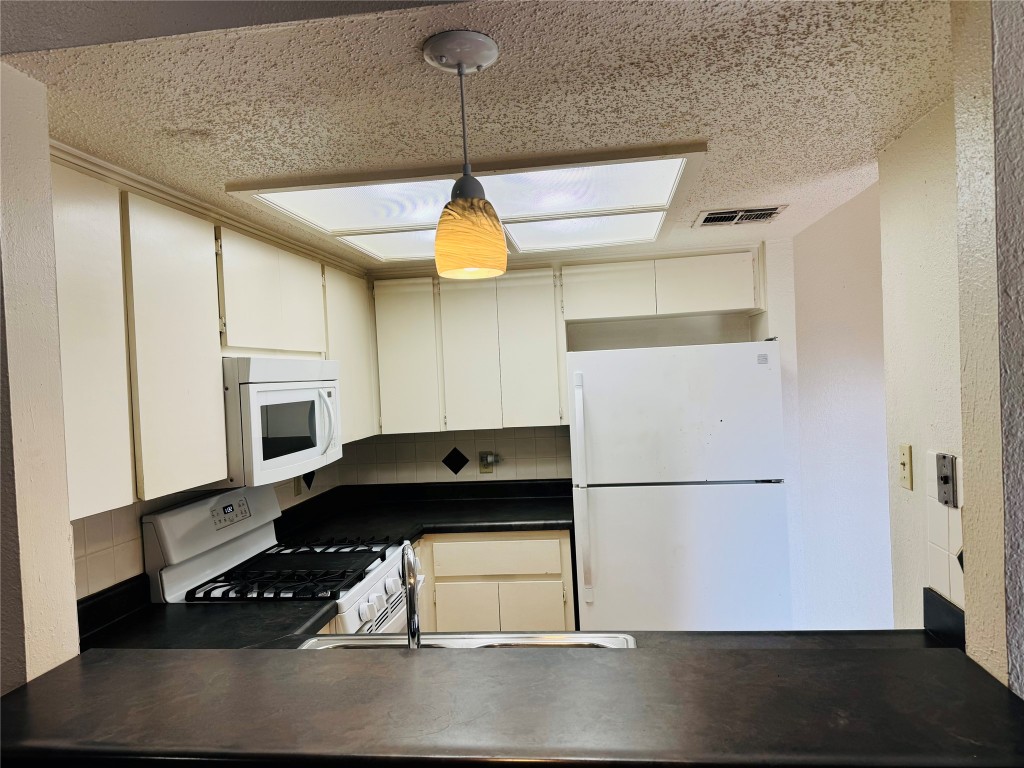 907 Milford Way, Unit A Austin, TX 78745 - Photo 9 of 16 a kitchen with a refrigerator a stove a microwave and wooden floor