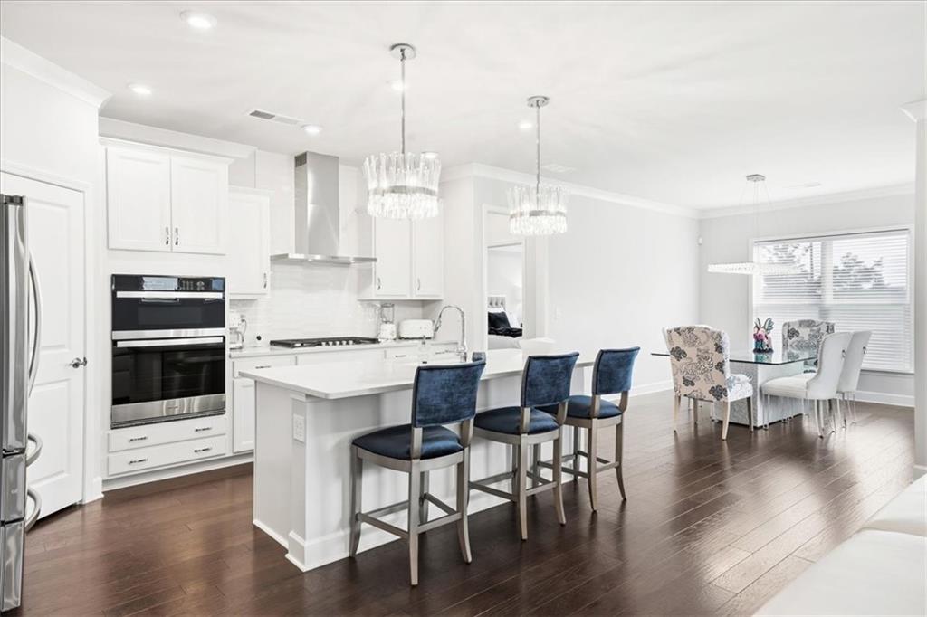 2457 Naples Street Hoschton, GA 30548 - Photo 5 of 41 a kitchen with stainless steel appliances kitchen island wooden floors and white cabinets