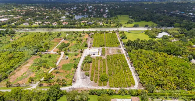 an aerial view of a residential houses with outdoor space and trees